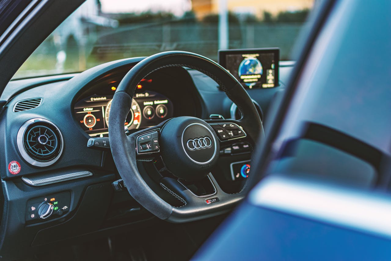 Explore the luxury Audi car interior featuring a sleek steering wheel and advanced dashboard display.
